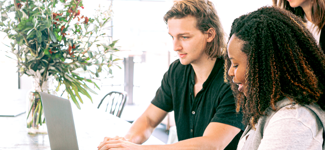 Deux jeunes entrepreneurs collaborant sur un ordinateur portable, illustrant l'attrait de la franchise pour les nouvelles générations de créateurs d'entreprises